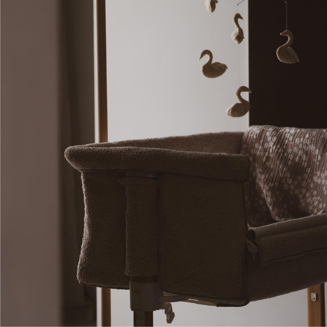 Quax Side by Side Co-Sleeper Crib in Natural Bouclé Sheep with swan mobile and soft blanket in parents bedroom