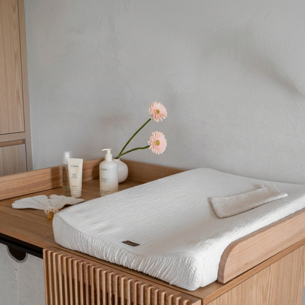 Quax Natural Clay muslin changing mat cover styled in a neutral contemporary nursery changing space.