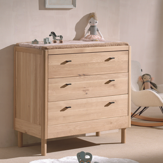 three drawer chest of drawers made of oak wood with baby changing mat on top.