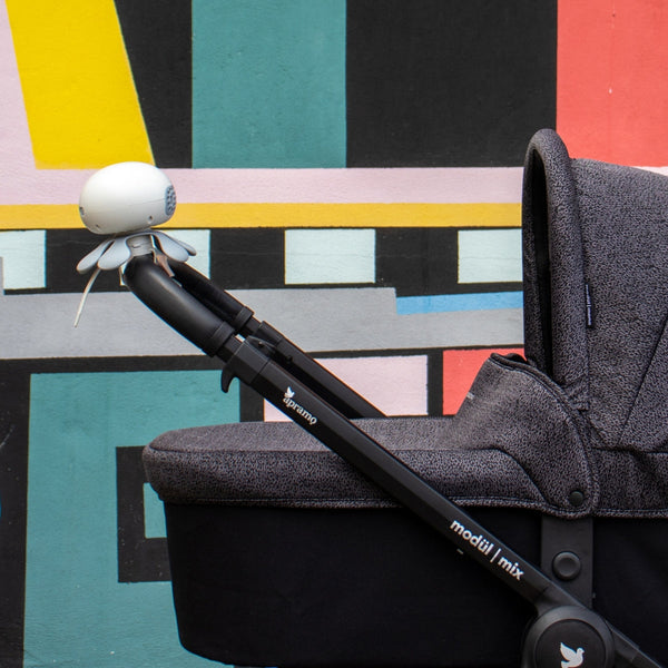 apramo stroller fan attached to black stroller handle in front of modern urban wall