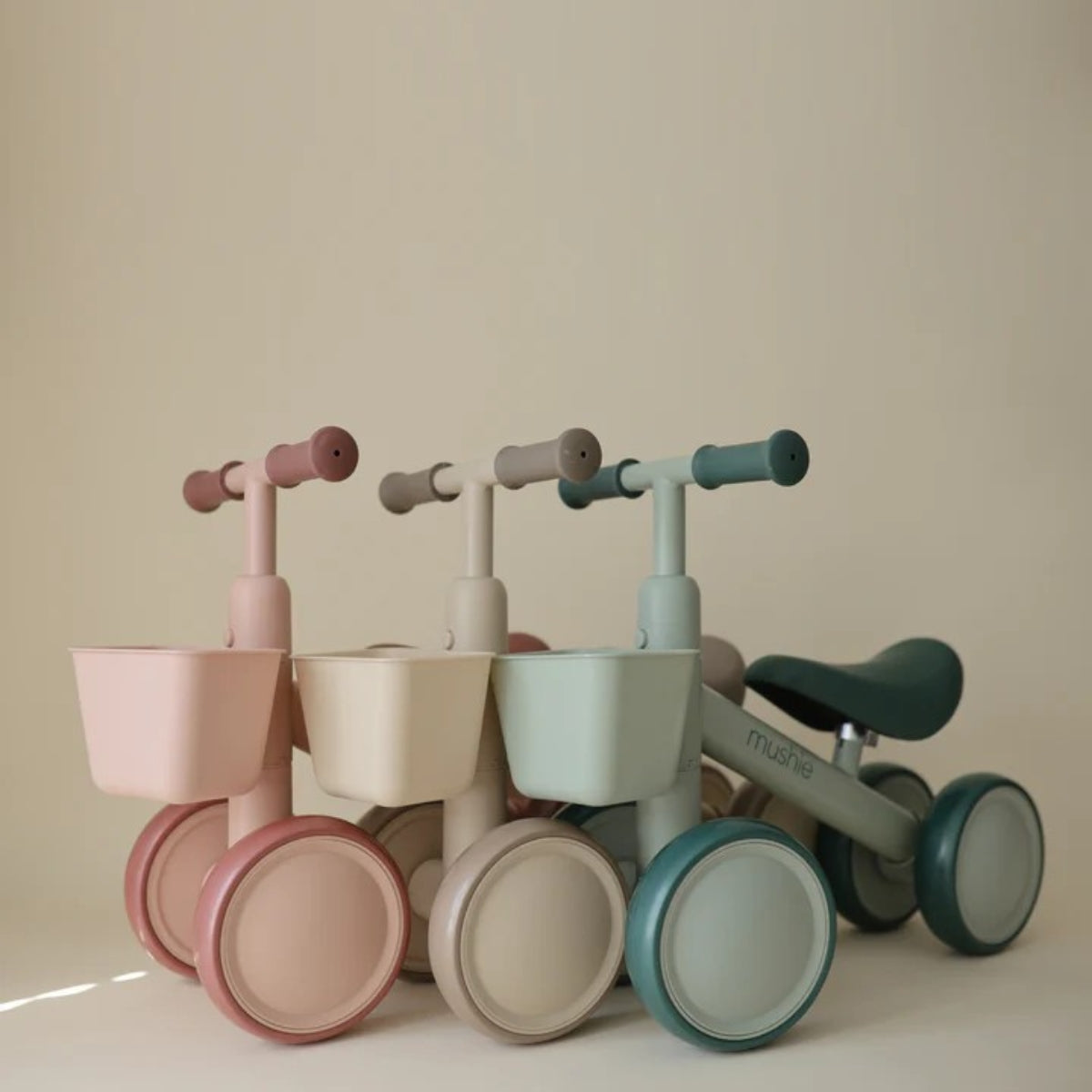 three Mushie Mini Toddler Bikes shing sand, sage and pink versions