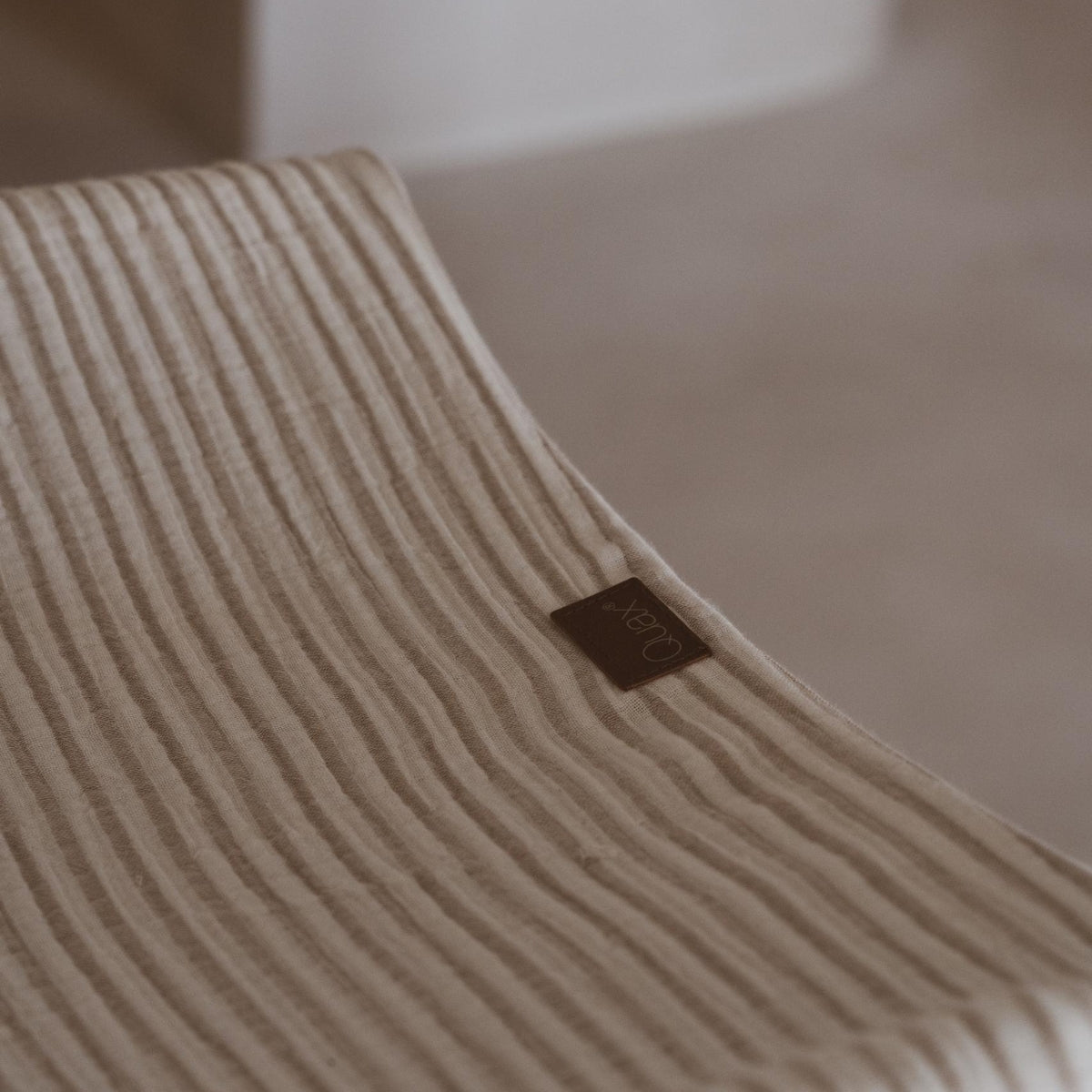 clouse up of Quax logo on removable washable Muslin Changing Pad Cover Natural Collection Stripes