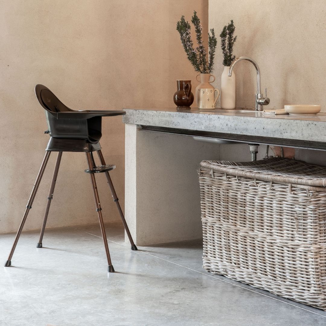 Modern kitchen with a quax ultimo 3 luxe highchair high chair, stone countertop, and wicker basket.