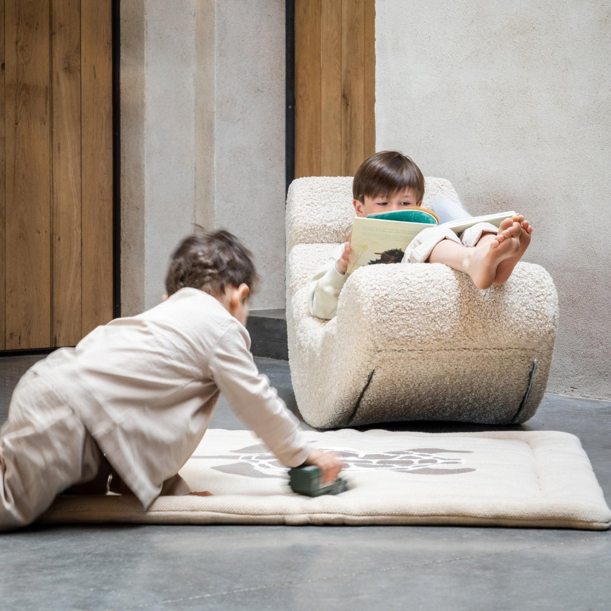 child reading a book while sitting on a Quax Rocking Banana Sheep teddy rocking chair
