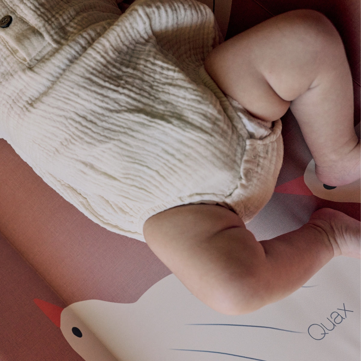 baby laying on a Quax Happy Birds wedge baby changing mat 70x50cm with raised sides