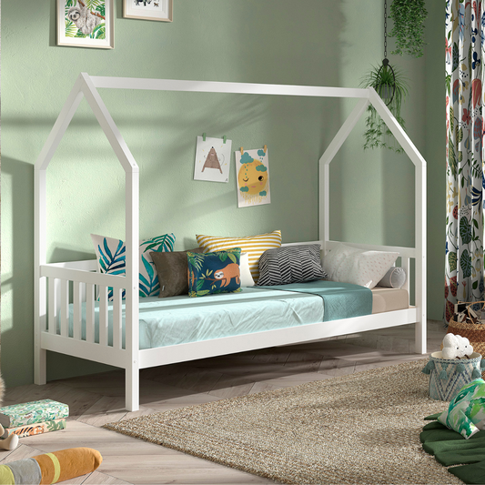 Sturdy looking FSC certified wooden white house shaped kids bed with guard rail on three sides. One side is left open for child to access bed or for older users to use as a sofa.  Bed has a comfy looking mattress and kids inspired bedding in clean and tidy bedroom. 