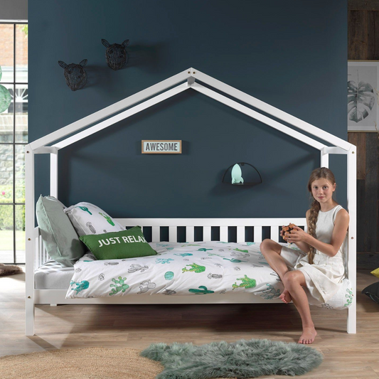 White VIPACK DALLAS house-shaped bed with a child sitting on it in a room with dark blue walls.