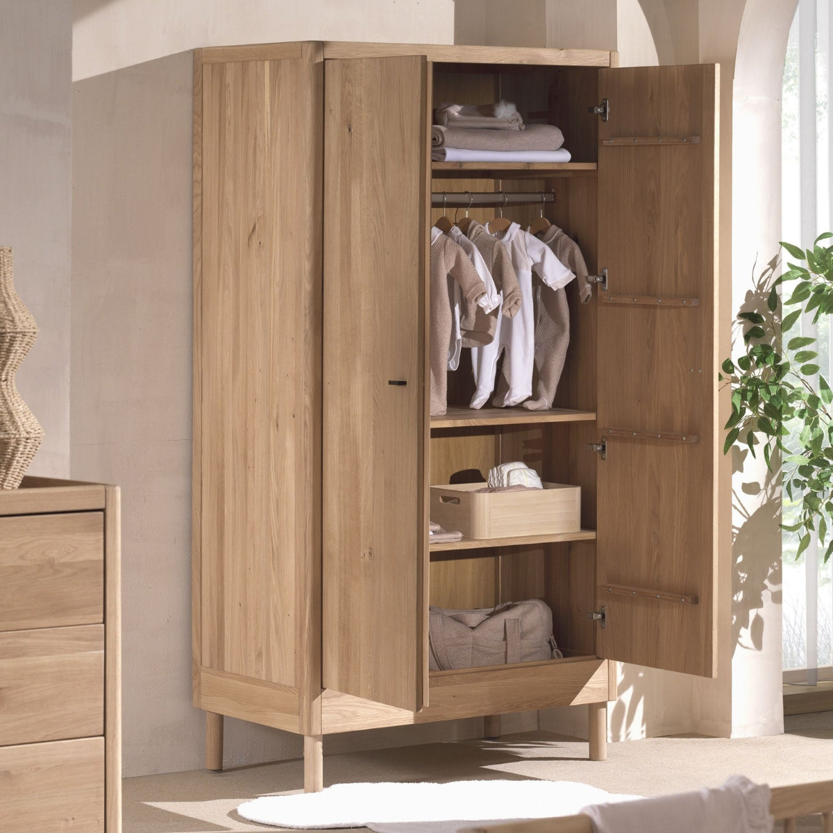 VIPACK FORREST solid oak 2 door wardrobe with doors open showing baby clothes in modern nursery
