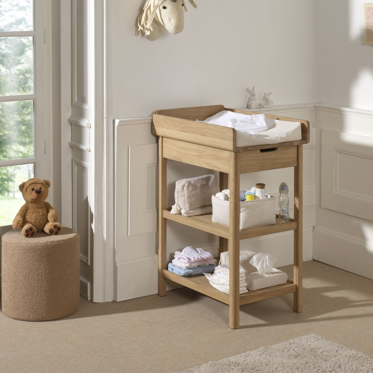 Traditional solid oak wooden baby changing table with a comfy changing pad and baby changing essentials in a nursery cosy setting