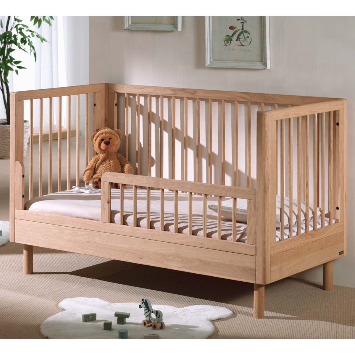 VIPACK JAXX FORREST oak wood cot bed 140x70cm being used with open side as a toddler bed with protective guard rail in modern european nursery