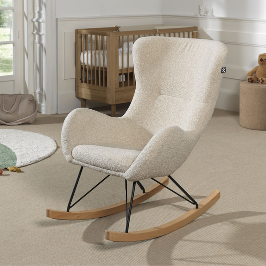 nursing chair with teddy boucle fabric in modern nursery with a wooden cot and baby changing bag in the background