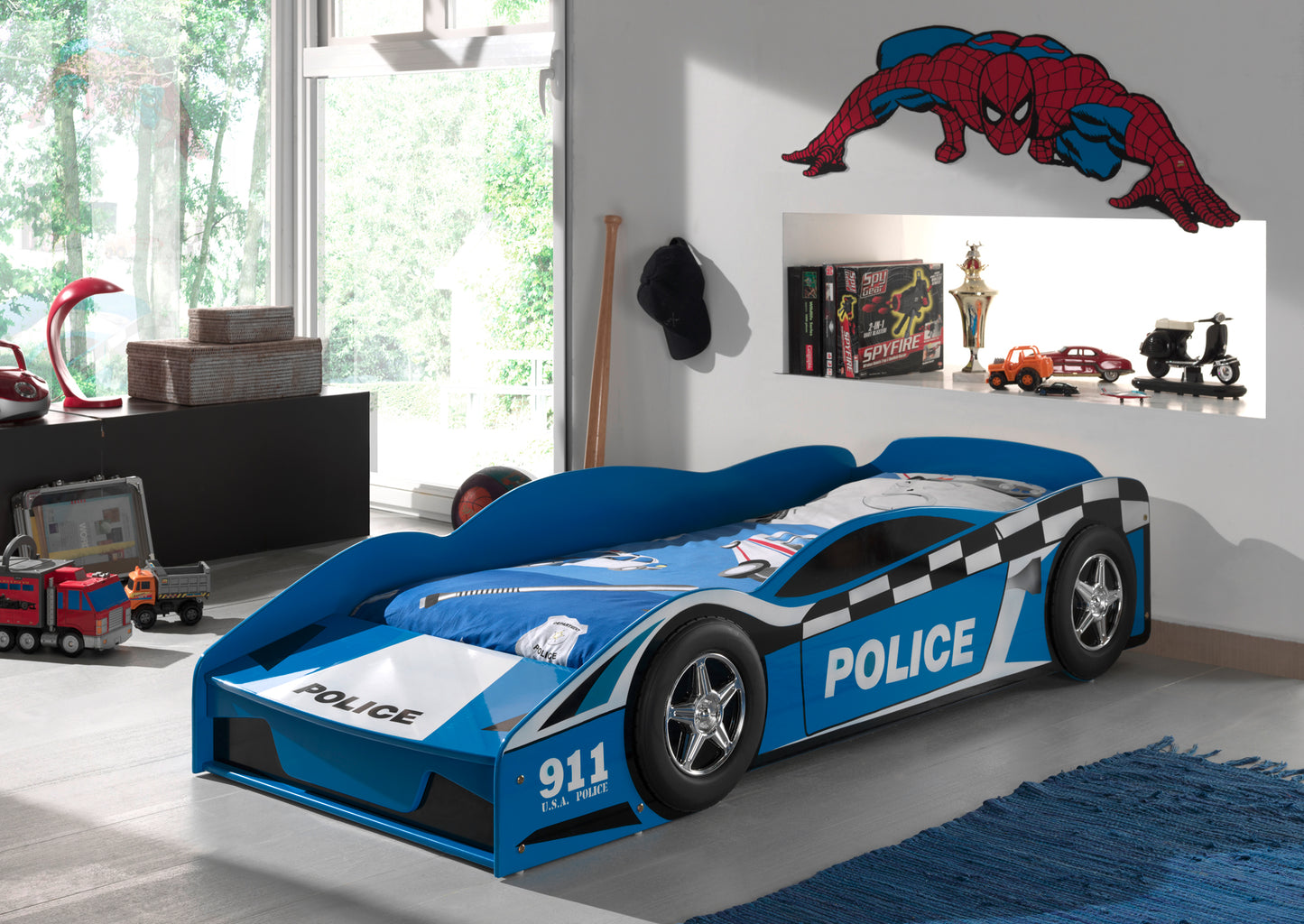 Children's VIPACK police car 140x70cm toddler bed in a room with Spider-Man poster and toys. Lifestyle image of toddlers room with blue police car toddler bed
