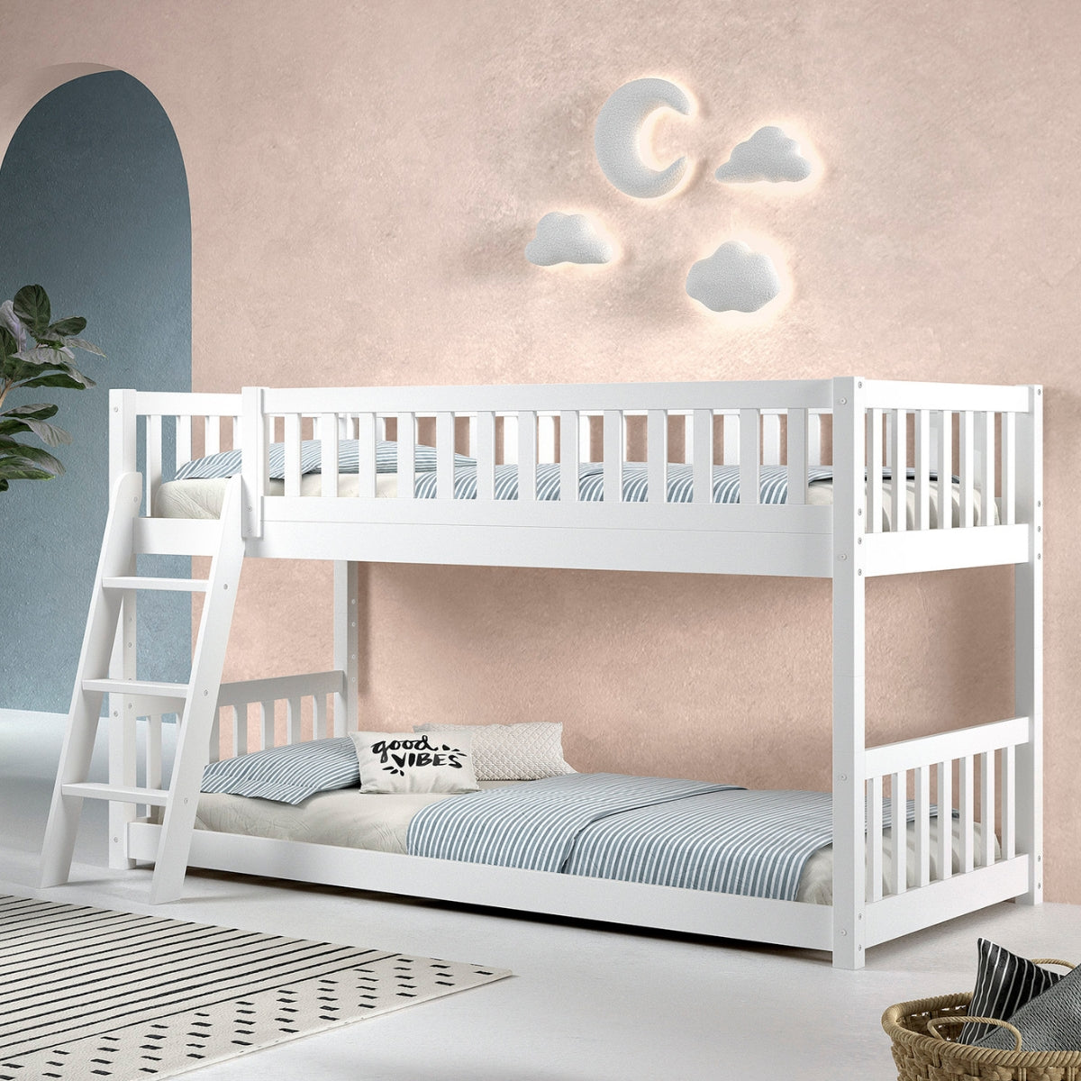 White wooden bunk bed with a low montessori floor bottom bunk in a room with decorative wall lights shaped like clouds and a moon.