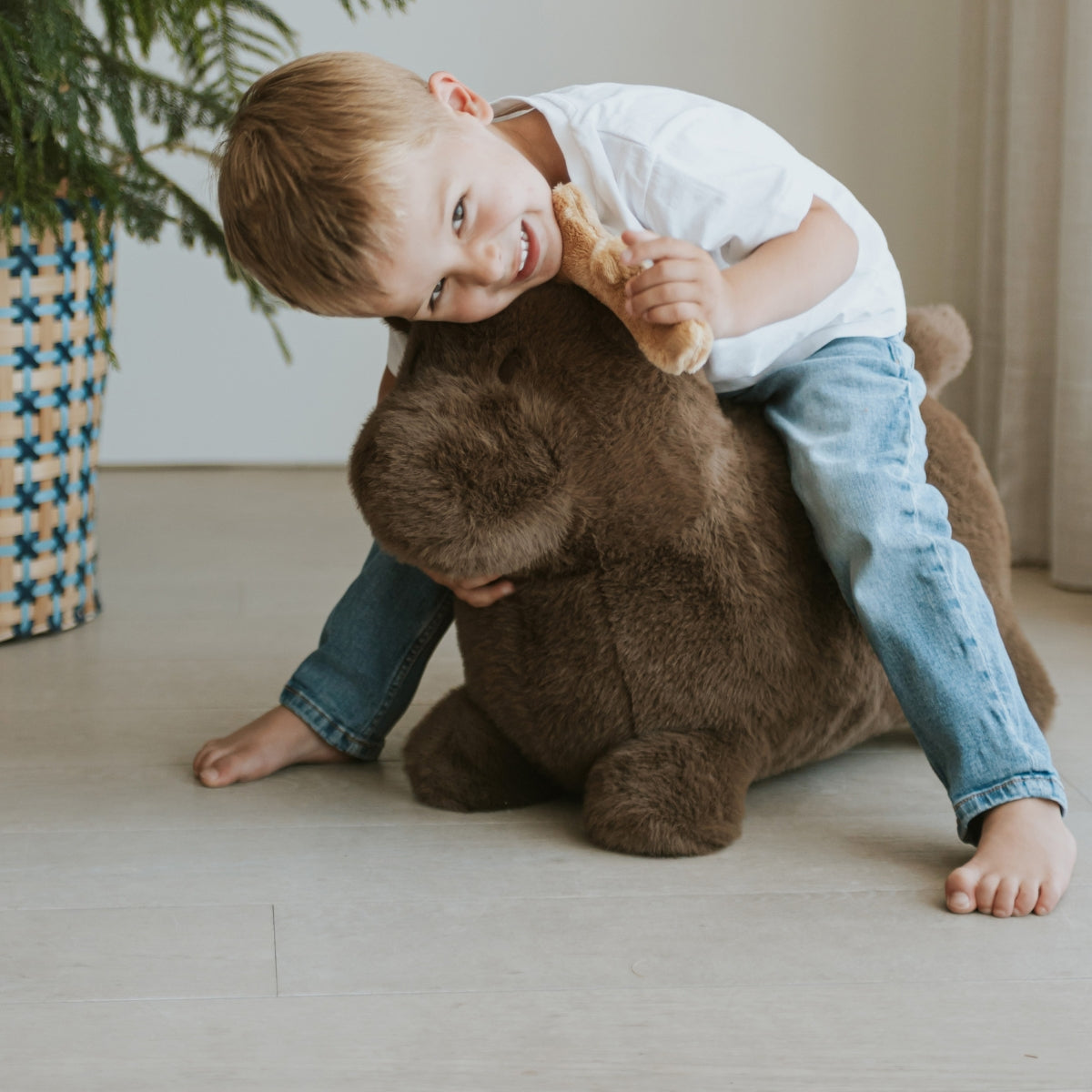 toddler riding a Wild & Soft Soft Bouncy Moose children's ride-on toy in living room