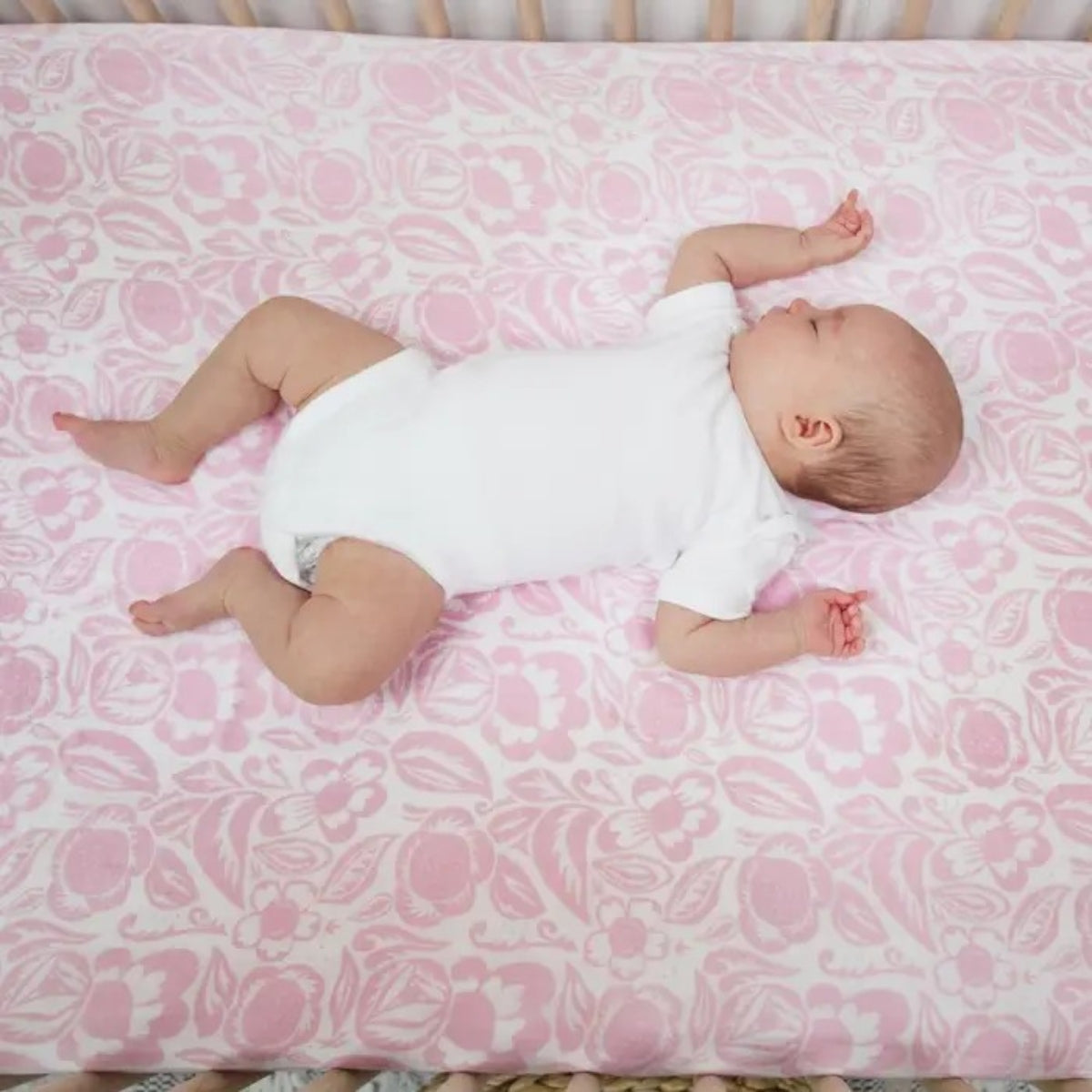 baby laying on pink aden + anais Essentials Cotton Muslin Swaddle Blanket Damsel.