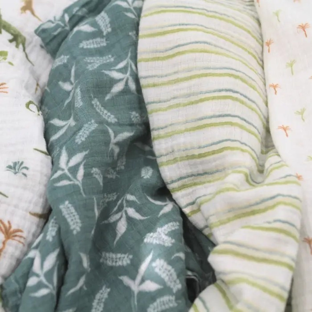 close up of Soft breathable 100% cotton muslin swaddle blankets in Dino Jungle print for swaddling, tummy time, nursing and everyday baby care.