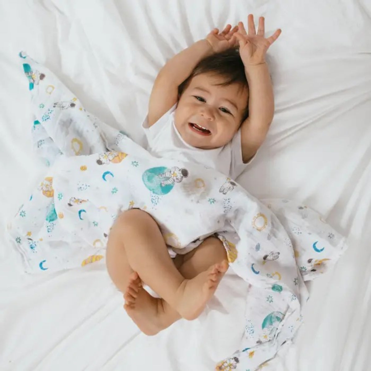 baby wrapped in aden + anais Cotton Muslin Swaddle blanket with space astronauts and planets pattern on