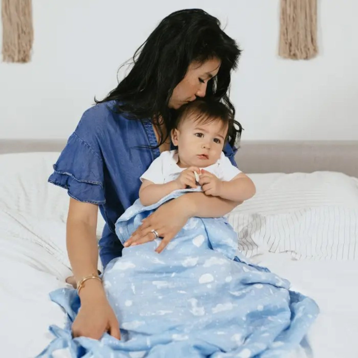 mother holding baby who is wrapped in a soft blue aden + anais Essentials Cotton Muslin Swaddle Blanket
