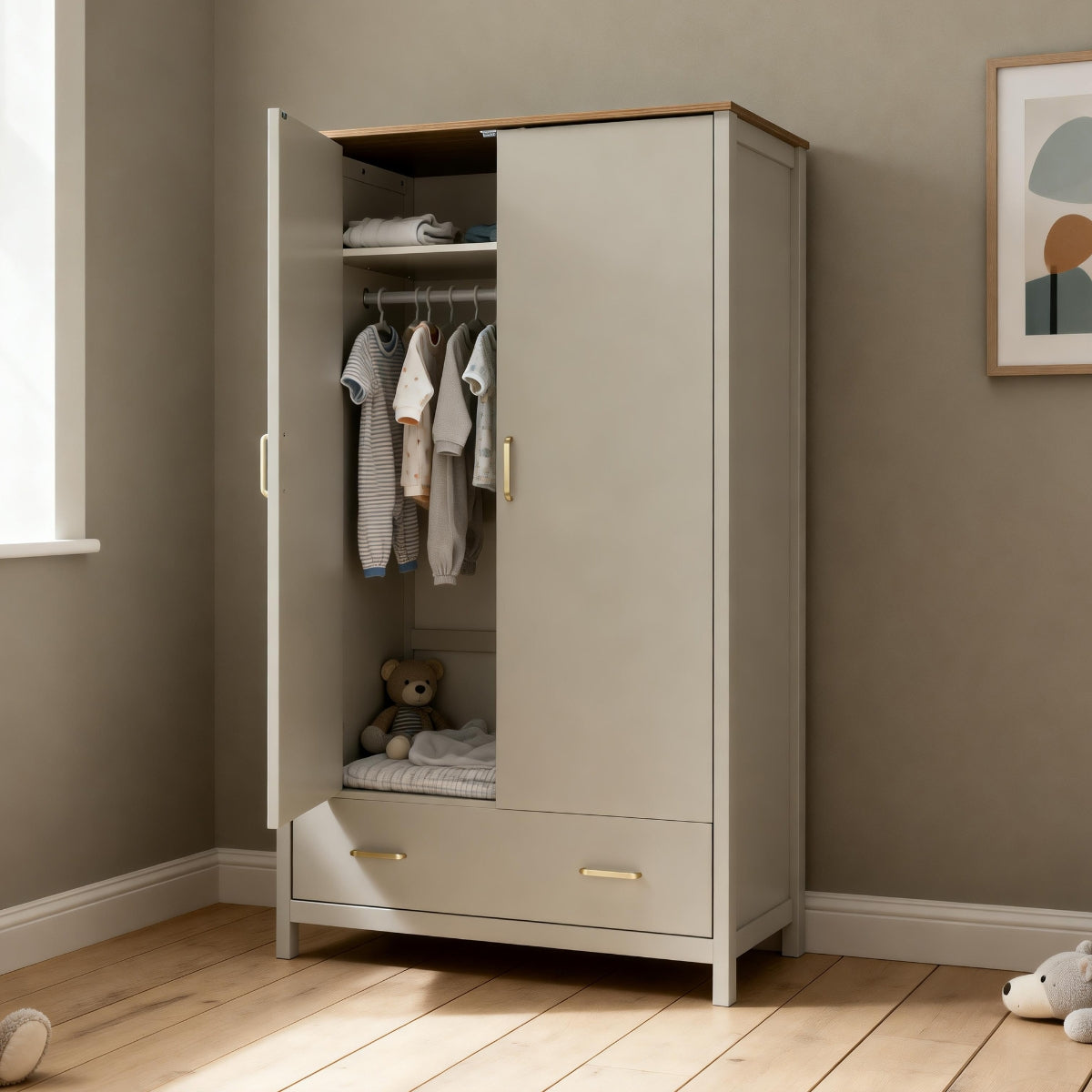 Babymore Mira Nursery Wardrobe in Cashmere Warm Oak with door open, showing internal shelf, hanging rail, baby clothes and full-width drawer