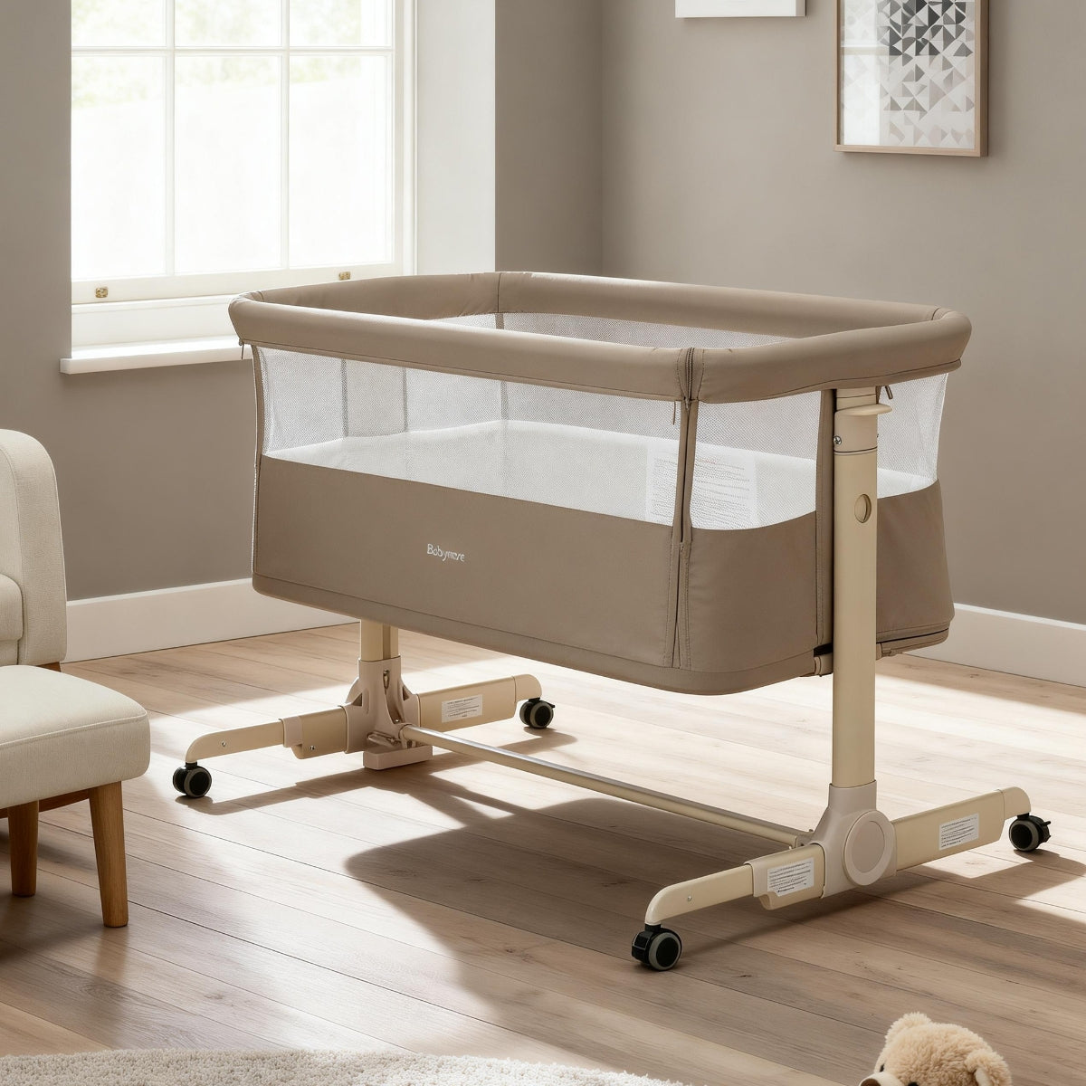 khaki babymore neera bedside crib in a room with a window and chair.