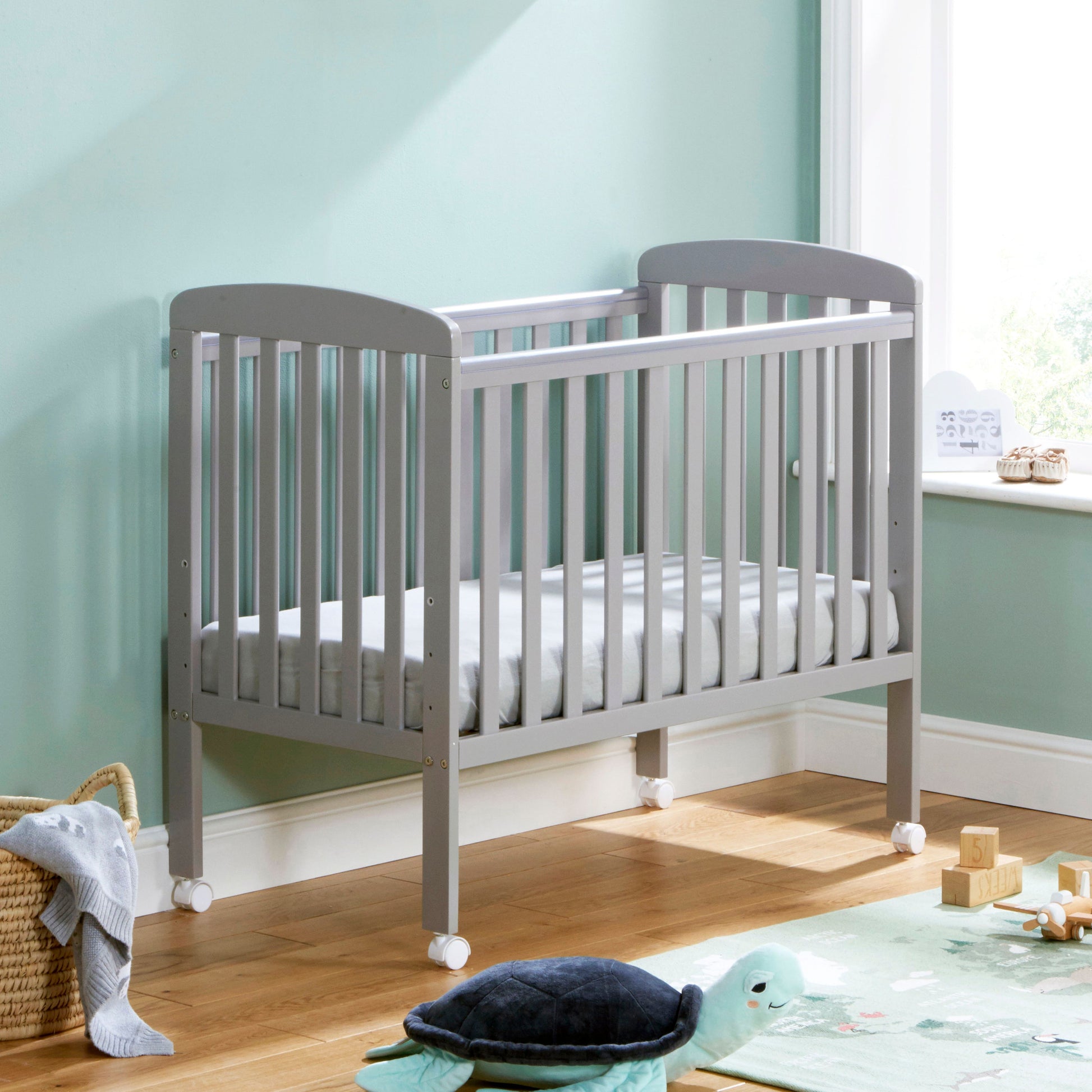 Babymore Space Saver Cot in grey with lockable wheels and adjustable base.