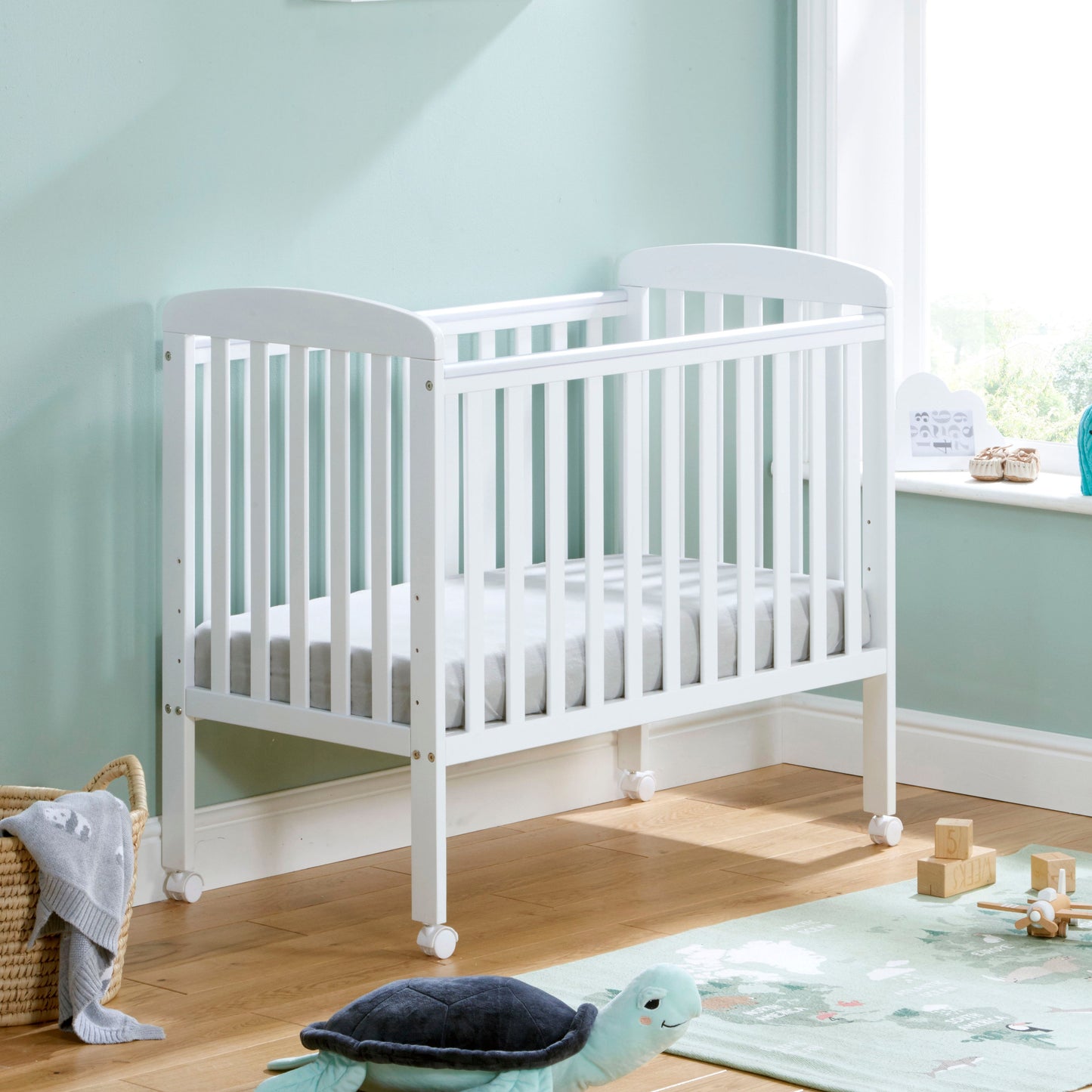 Babymore Space Saver Cot in white with lockable wheels and adjustable base.