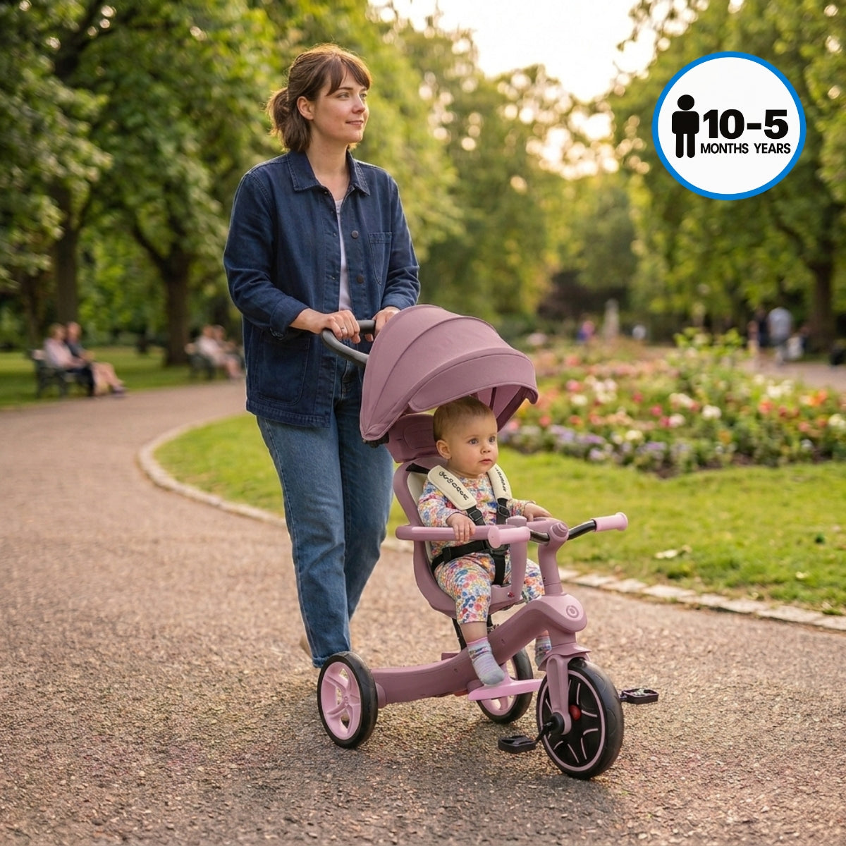 mother pushing young toddler in a Globber Explorer Trike Eco 4-in-1 in Berry in park on a sunny day