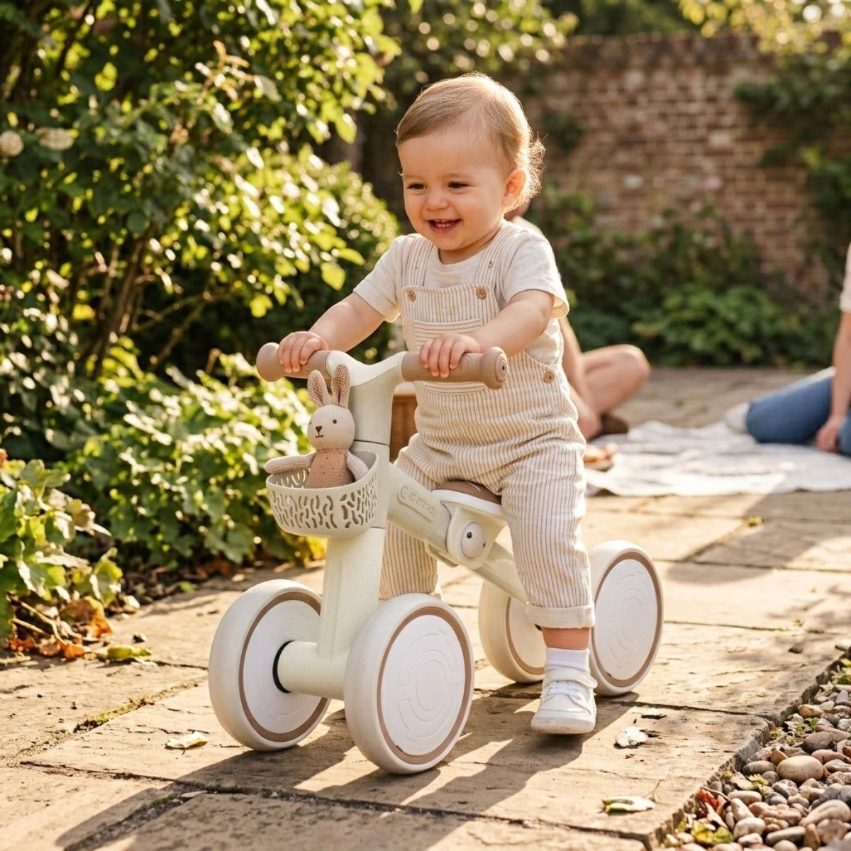 happy looking toddler riding a Globber Learning Bike Eco Coconut in sunny garden