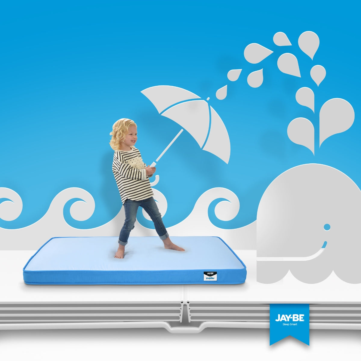 toddler standing on a jay-be waterproof mattress with a blue background and
