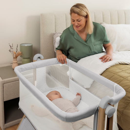 woman in bed looking at a baby in a grey Obaby Cloud bedside crib in modern bedroom 