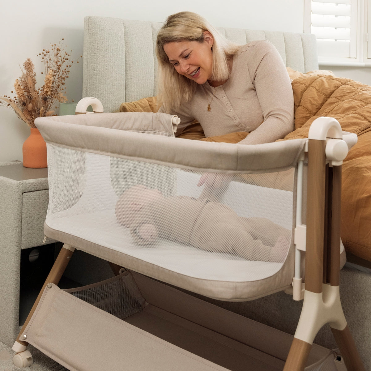 mother looking at baby in Obaby Cloud bedside crib in Oatmeal next to her bed
