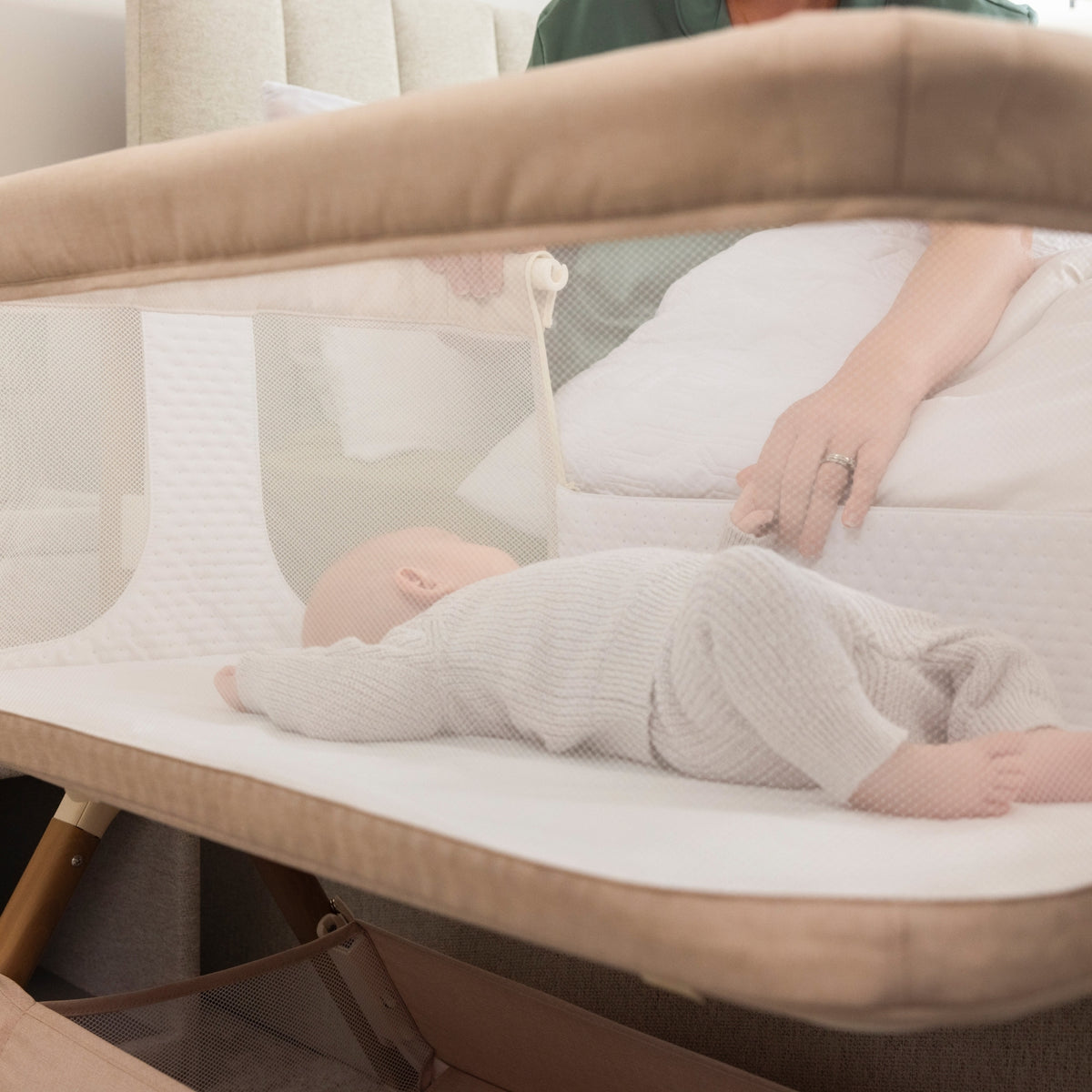 baby in a Obaby Cloud bedside crib in Oatmeal with mesh side panels