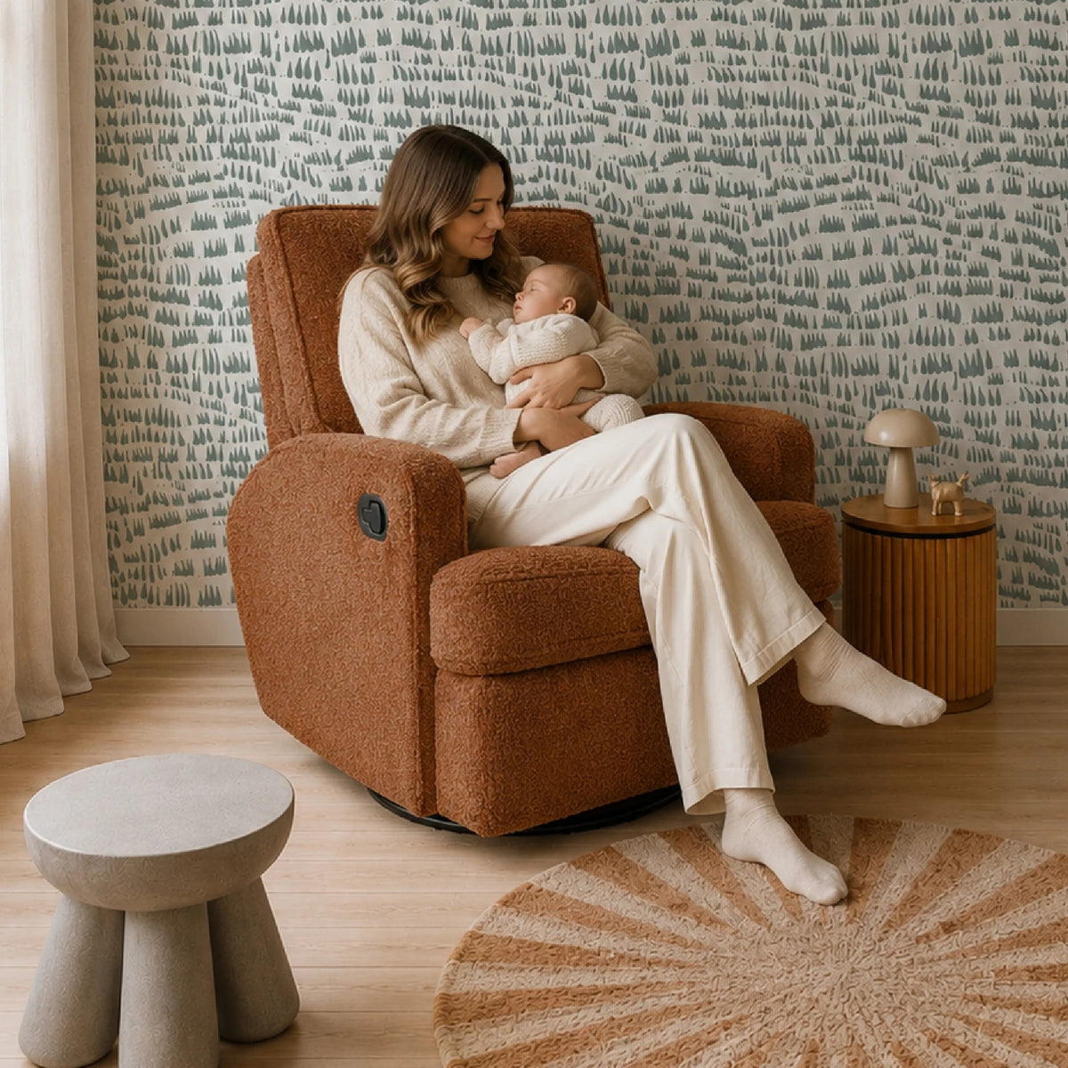 A mother sits in a Obaby Madison Chenille Marmalade nursing chair while holding a baby. 