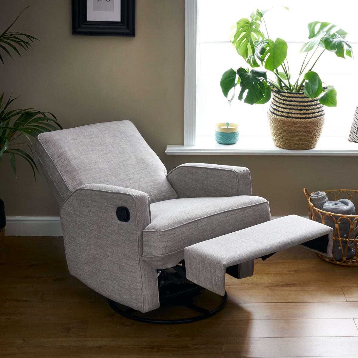 Obaby Madison swivel glider recliner nursing chair in Pebble upholstery with padded seat and backrest and legrest in living room