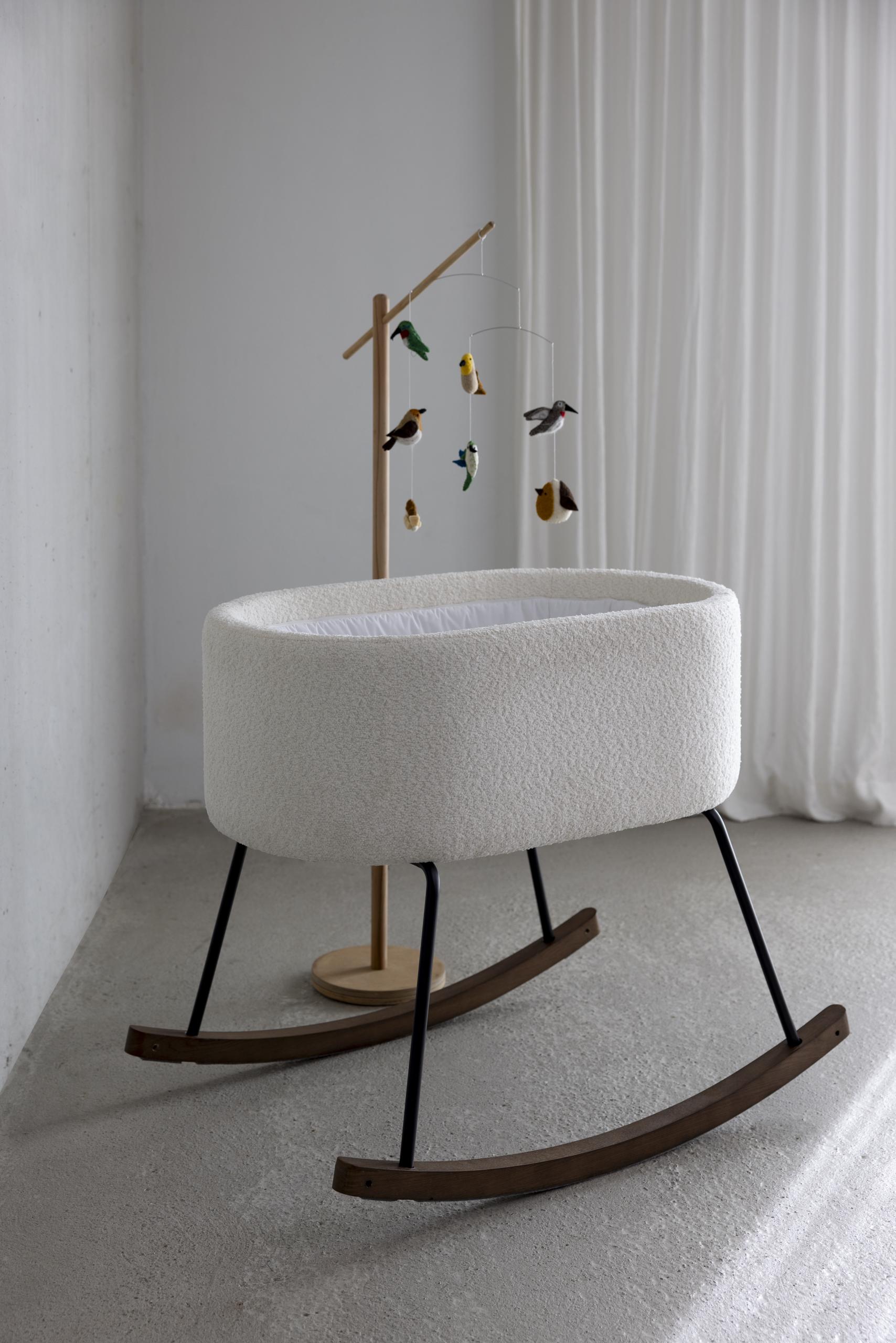 quax birds baby mobile hanging from wooden stand over boucle fabric rocking cradle deluxe in white nursery