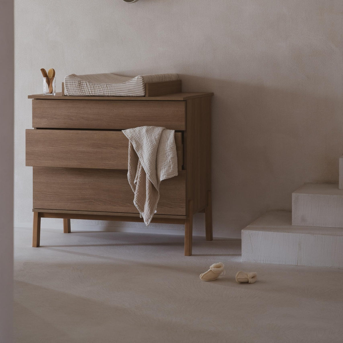 quax muslin baby blanket hanging from drawer of Quax ashi 3 drawer chest in modern home