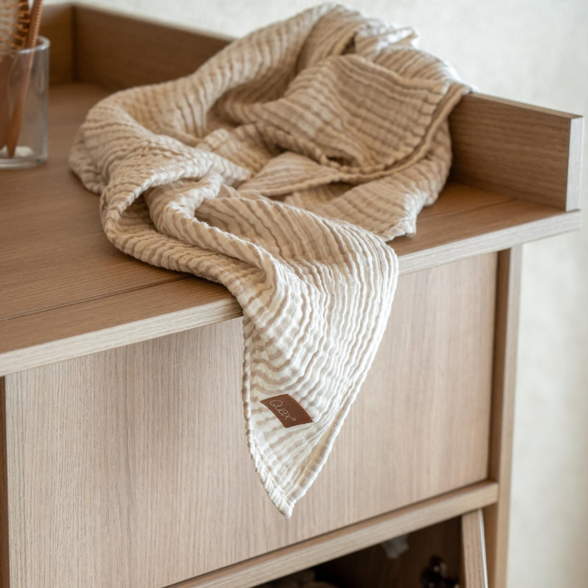 quax muslin baby blanket on light wood coloured nursery dresser in modern home