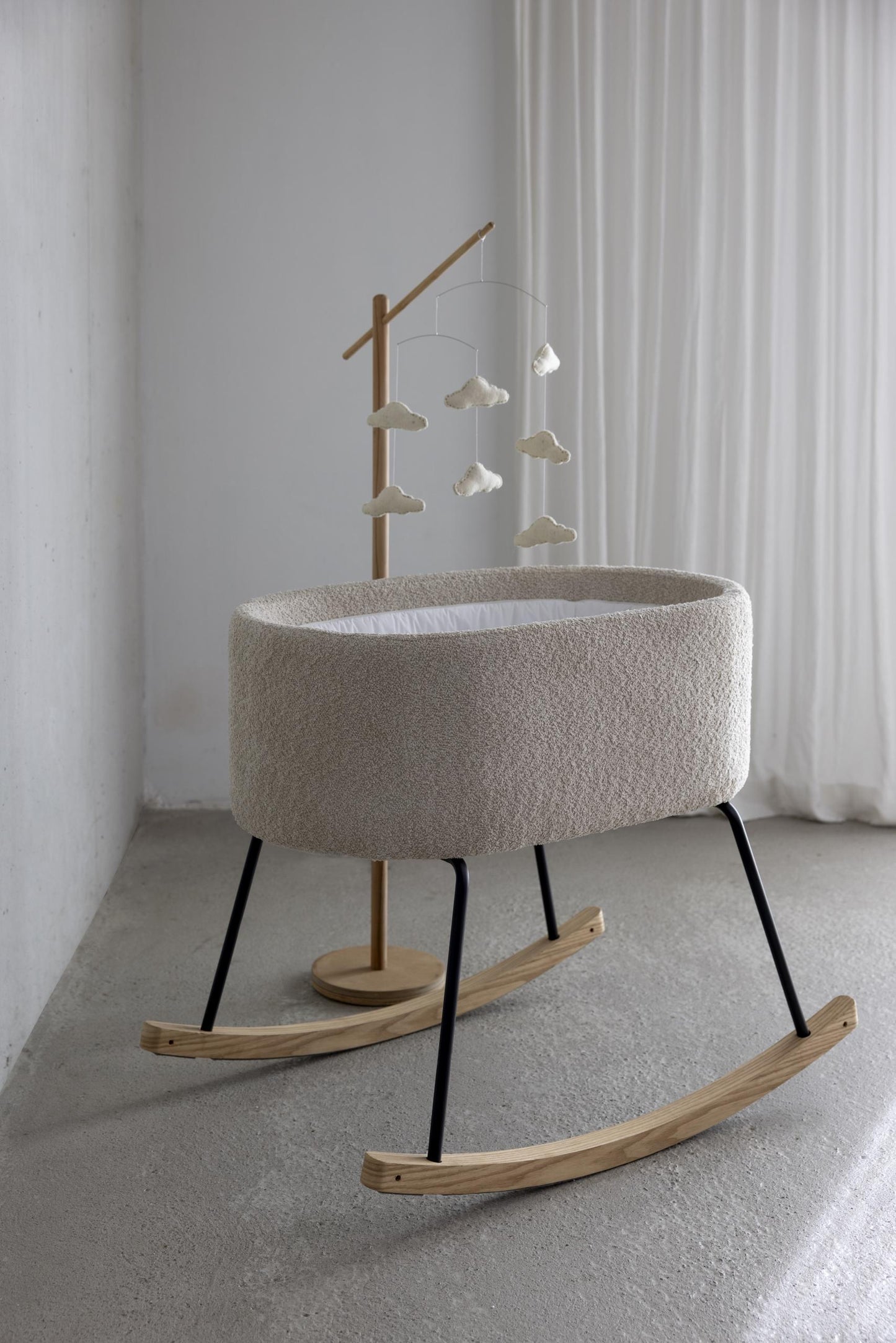 Quax deluxe cradle for newborn in soft cream boucle fabric with natural wooden rockers in modern scandi european nursery