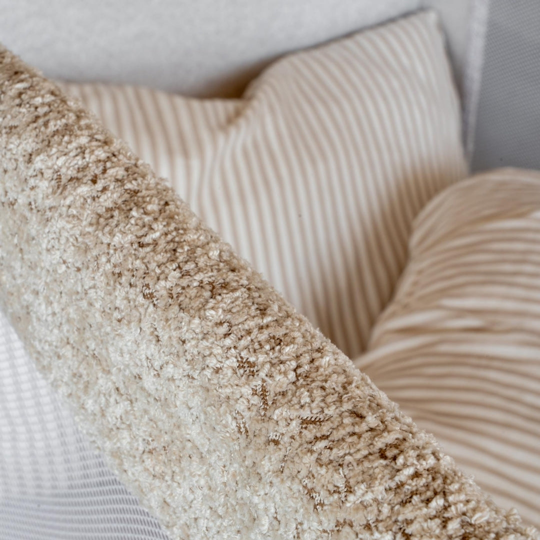 Close-up of textured beige pillows on a neutral background