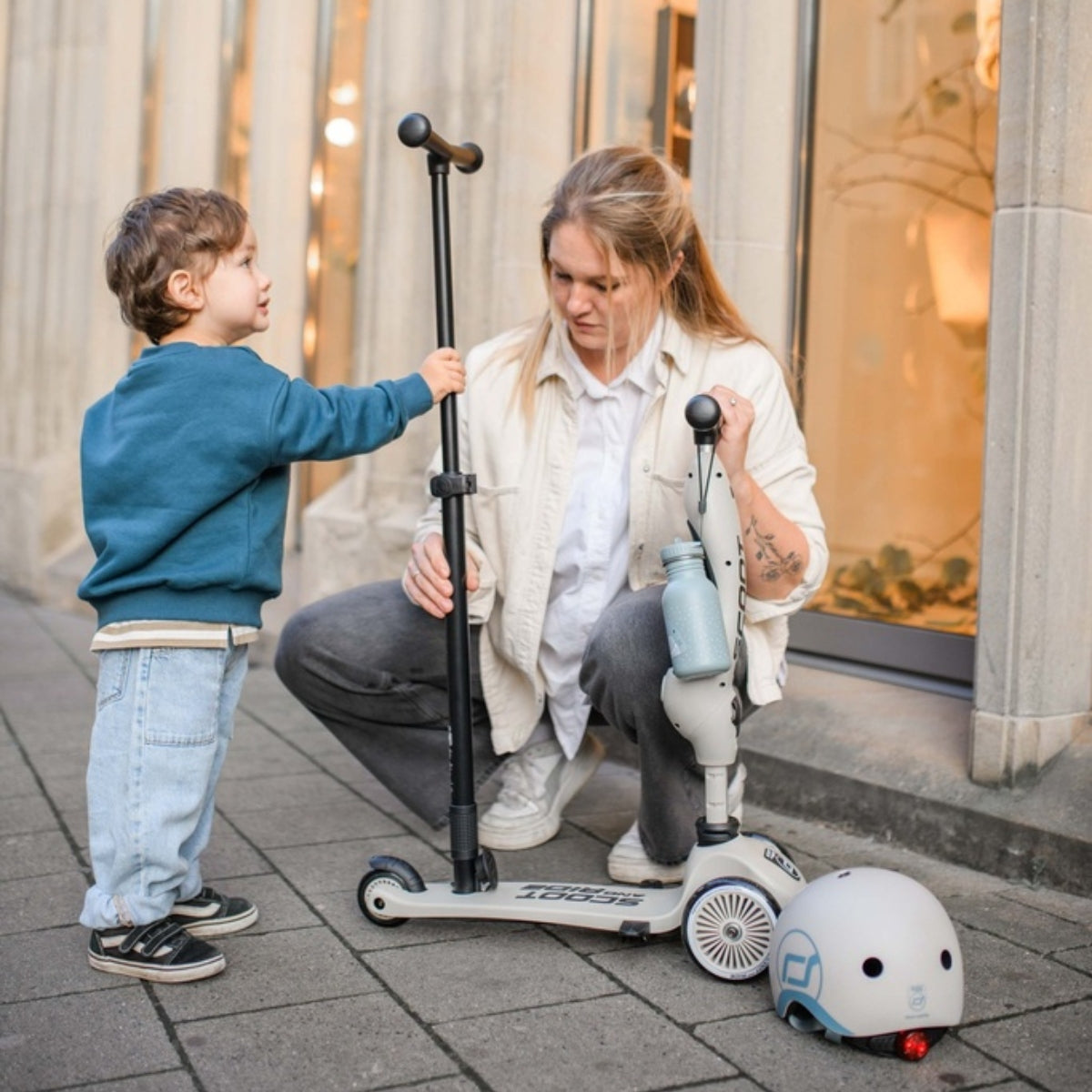 mum and toddler with scoot and ride highwaykick1 scooter and helmet in city street