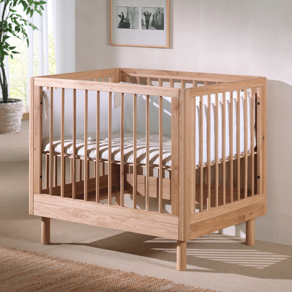solid oak baby play pen in natural wood colour with cushion and bumper in modern nursery
