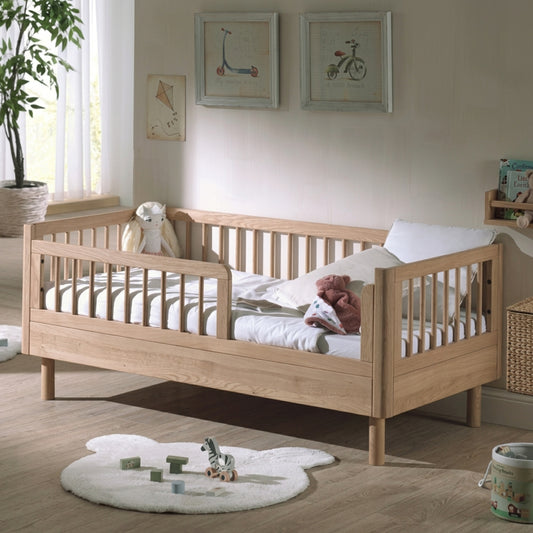 solid oak 140x70cm toddler bed with guard rails on bedroom with neutral decor