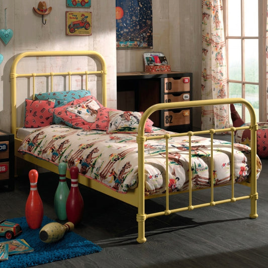 Children's bedroom with yellow metal single bed colorful bedding and toys.